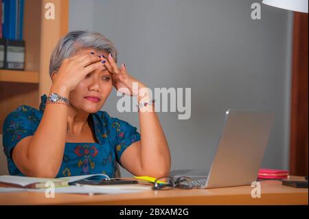 Ritratto espressivo di attraente stressata e overworking donna asiatica che lavora alla scrivania del computer portatile dell'ufficio in stress sentendosi frustrato e sconvolto dentro Foto Stock