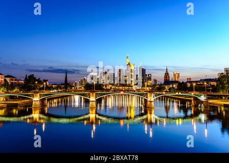 Splendida vista sullo skyline cittadino del centro di Francoforte sul meno, ponte con luci durante il tramonto all'ora blu, sera e notte. Finanza europea Foto Stock