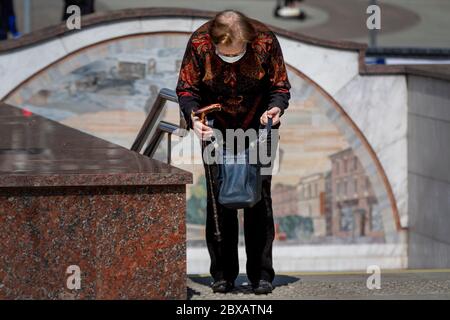 Mosca, Russia. 6 giugno 2020 una donna anziana in una maschera protettiva guarda nella sua borsa vicino all'ingresso della stazione della metropolitana Tverskaya nel centro di Mosca, Russia Foto Stock