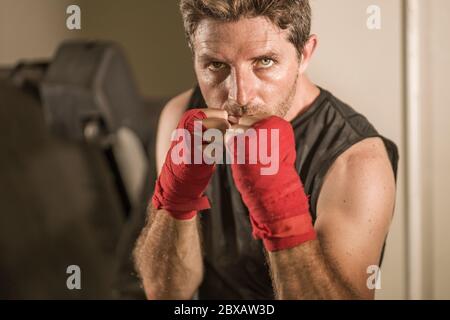 stile di vita palestra ritratto di giovane attraente e feroce uomo cercando formazione di boxe al club fitness facendo pesante borsa punzonatura allenamento con mani e strugi Foto Stock