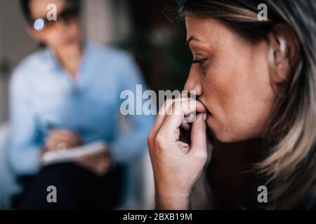 Donna con ansia che parla con un professionista della salute mentale Foto Stock