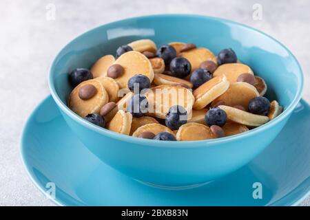 Colazione alla moda con mini pancake, mirtilli e patatine al cioccolato, vista dall'alto. Foto Stock