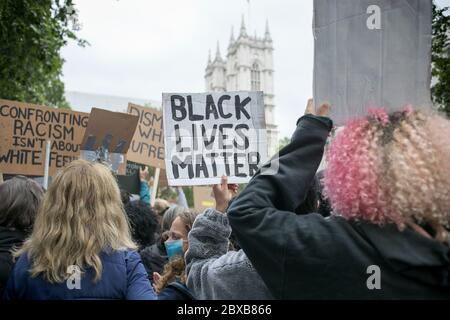 Manifestanti che hanno in mano cartelli che si affacciano sull'Abbazia di Westminster durante il raduno contro il razzismo sistemico nel Regno Unito, tenutosi nel centro di Londra. Foto Stock