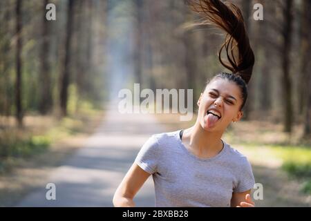 Bella giovane donna in esecuzione nel parco verde sulla soleggiata giornata estiva Foto Stock