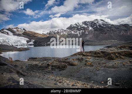 coppia in un ghiacciaio, vicino a un lago, montagne con neve in cima, nuvole e cielo blu Foto Stock