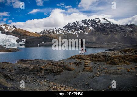 coppia in un ghiacciaio, vicino a un lago, montagne con neve in cima, nuvole e cielo blu Foto Stock