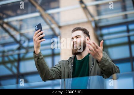 Chattare e incontrare gli amici online. Bearded man chattare online via cellulare. Riunione online. Conferenze audio o video su dispositivo mobile. Online Foto Stock
