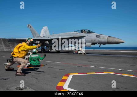 L'equipaggio della marina statunitense segnala un aereo da combattimento F/A-18E Super Hornet, attaccato ai maces reali dello Strike Fighter Squadron 27, per il lancio sul ponte di volo della portaerei di classe Nimitz USS Ronald Reagan 2 giugno 2020 in corso nel Mare delle Filippine. Foto Stock