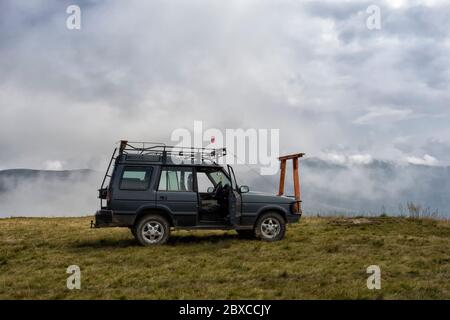 SUV auto su una cima di montagna con nuvole intorno. Alla ricerca di avventura Foto Stock