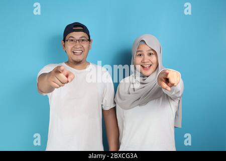 Portait di felice coppia musulmana asiatica sorridente e indicando la macchina fotografica, marito e moglie abbracciare pieno di amore, concetto di famiglia Foto Stock