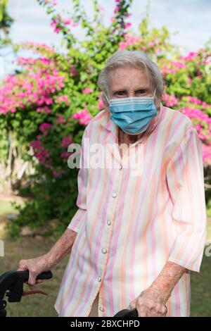 Anziana signora indossare maschera ottenere esercizio andare per una passeggiata in giardino Foto Stock