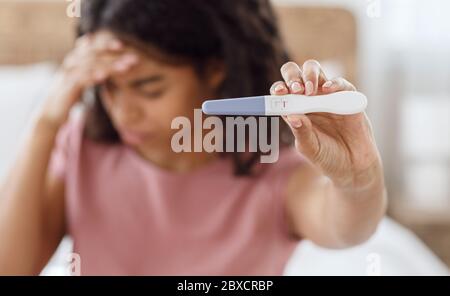 Donna nera depressa che tiene negativo test di gravidanza Foto Stock