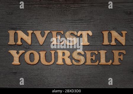 Investite in voi stessi. Concetto di business per la tipografia di testo di auto motivazione scritta su alfabeto di legno Foto Stock