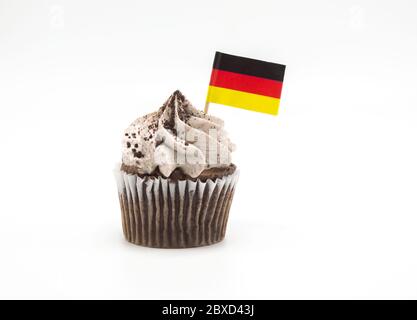 Un biscotti al cioccolato e una cupcake alla crema con una piccola bandiera tricolore tedesca stuzzicadenti incastrati in esso, isolato su bianco Foto Stock