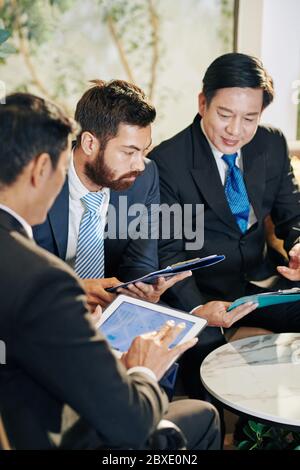 Le persone che lavorano per le aziende discutono di grafici e diagrammi durante la riunione e discutono della crescita aziendale in pandemia Foto Stock