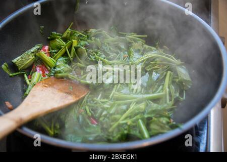 "Pad Pak Boong" un piatto tradizionale tailandese: Mescolare le verdure fritte 'Morning Glory' (Ipomoea aquatica) alla griglia in un wok Foto Stock