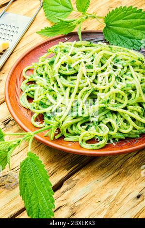 Pasta italiana tradizionale con salsa di ortica alle erbe. Pasta verde su tavola di legno. Foto Stock