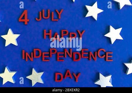 Le parole 4 luglio Happy Independence Day lettere in legno rosso dipinte a mano per un aspetto patriottico. Stelle sullo sfondo. Celebrazione. Biglietto di auguri. Via superiore Foto Stock