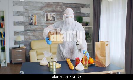 Volontari in scatola di tenuta di Hazmat Suit mentre si mette il cibo in esso. Foto Stock