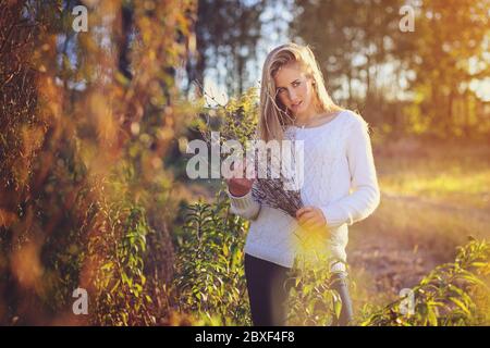 Bella donna che si pone in un campo . Colori del tramonto Foto Stock