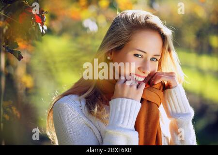 Bella donna sorridente in calda luce autunnale. Ritratto retroilluminato stagionale Foto Stock