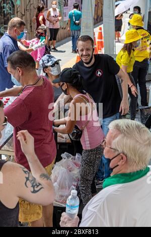 Volontari con maschere e guanti che danno cibo gratuito in cucina di strada durante la pandemia di Covid, Bangkok, Thailandia Foto Stock