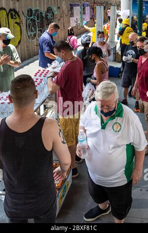 Volontari con maschere e guanti che danno cibo gratuito in cucina di strada durante la pandemia di Covid, Bangkok, Thailandia Foto Stock