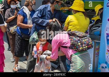 Volontari con maschere e guanti che danno cibo gratuito in cucina di strada durante la pandemia di Covid, Bangkok, Thailandia Foto Stock