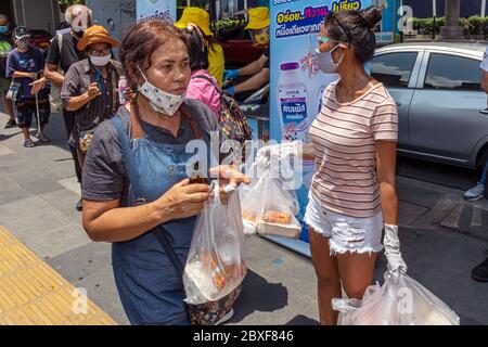 Volontari con maschere e guanti che danno cibo gratuito in cucina di strada durante la pandemia di Covid, Bangkok, Thailandia Foto Stock