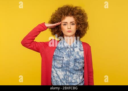 Sì Signore! Ritratto di donna responsabile seria con capelli ricci che dà saluto, ascoltando attentamente l'ordine e la disciplina seguente, porco obbediente Foto Stock