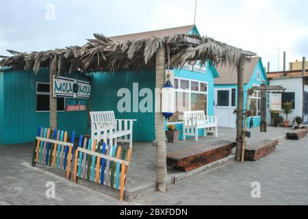 Walvis Bay, Namibia - 25 aprile 2015: Costa atlantica con molo al tramonto. Ristorante vuoto sul molo. Foto Stock