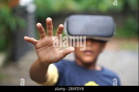 Ragazzo che indossa un dispositivo VR, sorpreso dalla realtà virtuale Foto Stock