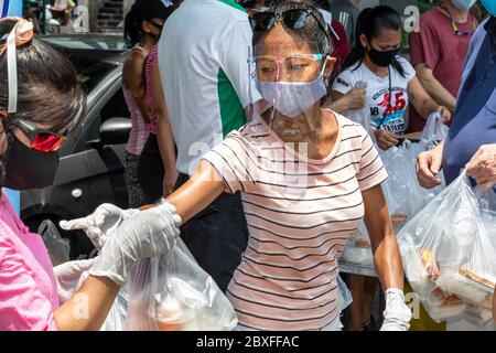 Volontari con maschera facciale e guanti che danno fuori cibo gratuito presso la banca alimentare durante la pandemia di Covid, Bangkok, Thailandia Foto Stock