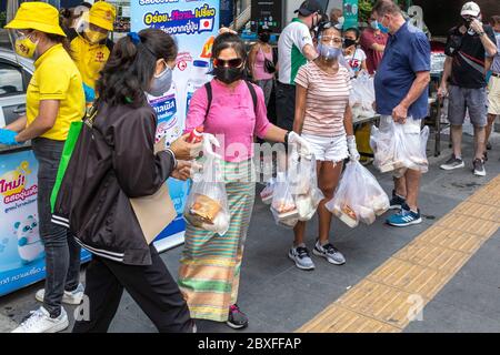 Volontari con maschera facciale e guanti che danno fuori cibo gratuito presso la banca alimentare durante la pandemia di Covid, Bangkok, Thailandia Foto Stock