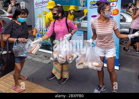 Volontari con maschera facciale e guanti che danno fuori cibo gratuito presso la banca alimentare durante la pandemia di Covid, Bangkok, Thailandia Foto Stock