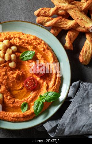 Hummus vegano al pomodoro con grissini e basilico Foto Stock