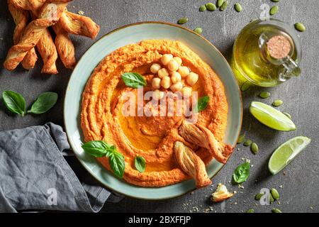 Goditi il tuo hummus di pomodoro con grissini e basilico Foto Stock