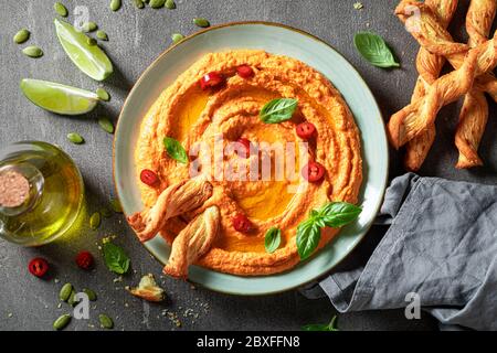 Hummus vegano al pomodoro con olive, basilico e grissini Foto Stock