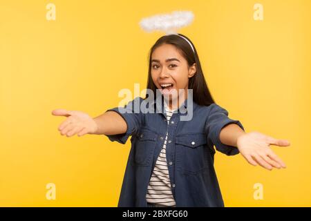 Vieni tra le mie braccia! Ritratto di generosa ragazza angelica con nimbus che tiene le mani aperte ad abbracciare, dando un caloroso benvenuto, saluto e condivisione lo Foto Stock