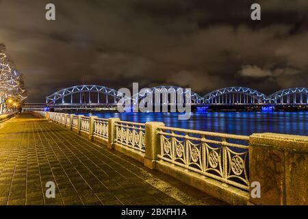 RIGA, LETTONIA - 2 GENNAIO 2017: Il ponte ferroviario di riga di notte che attraversa il fiume Daugava Foto Stock