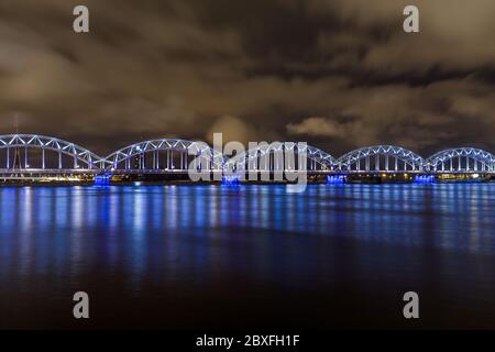 RIGA, LETTONIA - 2 GENNAIO 2017: Il ponte ferroviario di riga di notte che attraversa il fiume Daugava Foto Stock