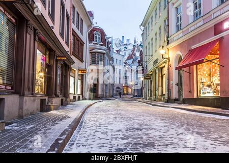 TALLINN, ESTONIA - 4 GENNAIO 2017: Una vista lungo la via Pikk nella città vecchia di Tallinn al mattino durante l'inverno. Neve, una persona, ristoranti e negozi Foto Stock