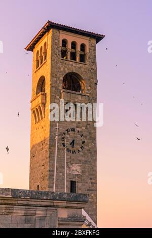 Lungomare al tramonto intorno al campanile della Chiesa dell'Annunciazione della Vergine, Rodi città, Dodecanese, Grecia Foto Stock