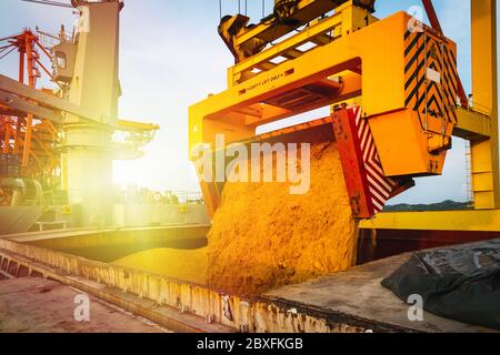 Zucchero greggio caricato in grande foro del recipiente dal rotainer per l'esportazione. Trasporto e manipolazione di prodotti alla rinfusa di zucchero. Concetto agroindustriale. Foto Stock