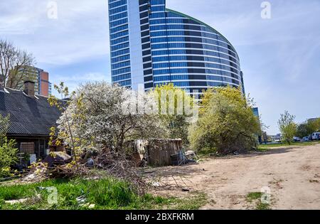 Rifiuti e vecchio edificio in legno vicino al nuovo grattacielo Foto Stock