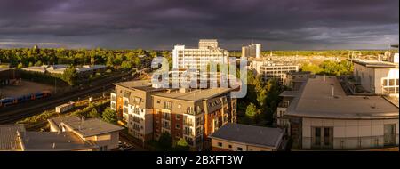 Una vista panoramica aerea dall'alto di un cielo tempestoso con le precipuose discese durante il tramonto con una suggestiva illuminazione sul centro di Basingstoke con appartamenti, Regno Unito Foto Stock