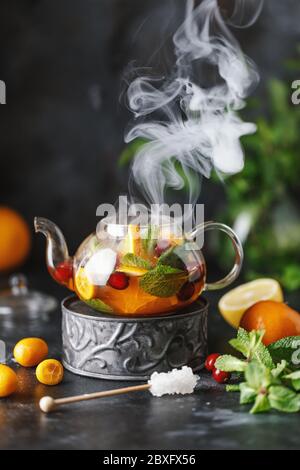 Tè alla frutta con menta, arance e mirtillo rosso su sfondo di pietra scuro. Una tazza di tè caldo Foto Stock