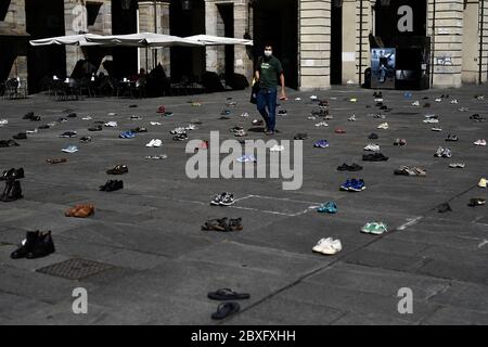 Torino, Italia - 05 giugno 2020: Un uomo cammina tra coppie di scarpe durante un venerdì per una futura dimostrazione, uno sciopero climatico mondiale contro l'inazione governativa verso il crollo del clima e l'inquinamento ambientale. Credit: Nicolò campo/Alamy Live News Foto Stock