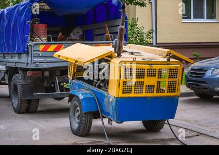 Auto con generatore. Ristrutturazione concettuale, lavori di riparazione della strada principale in città, costruzione di strade. Foto Stock