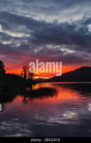 Lago Lantthe, Harihari, Costa Ovest, Nuova Zelanda. Specchio lago paesaggio, bellissimo tramonto. Foto Stock